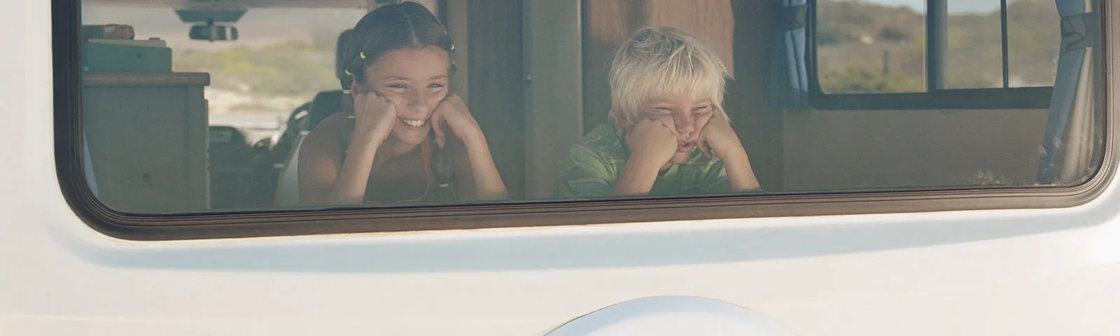 Kids looking out of a campervan window